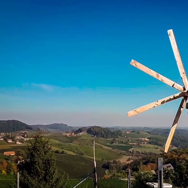 Das Bild zeigt die Aussicht vom Buschenschank Samenkönig in südsteirische Weinberge. Am rechten Bildrand sieht man noch Teile einer Klapotetz.