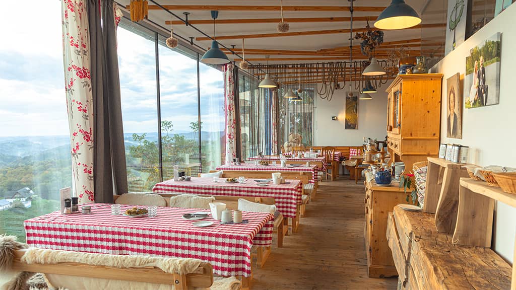 Das Bild zeigt einen Raum vom Buschenkschank mit Glasfront und Aussicht in die Südsteirischen Weinberge.